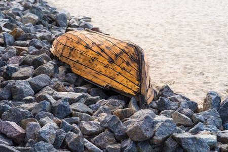 An old wooden boat lying on the stones closeup on the coastの写真素材