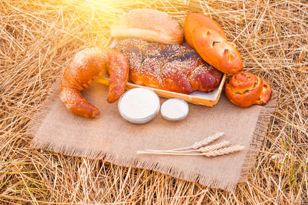 Bakery products lying on a tablecloth and wheat straw in field, closeupの写真素材