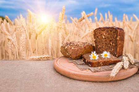 fresh breadand flowers lying on table, wheat field