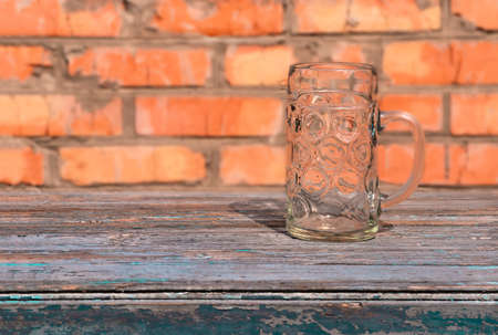 large beer glass mug, standing on an old table on a brick wall backgroundの写真素材