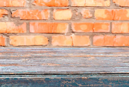 An old painted, peeling, wooden table on the background of a brick wallの写真素材