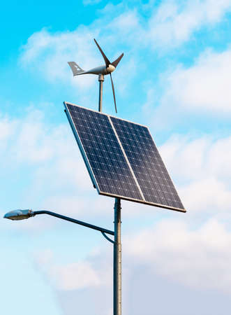 Solar panel and wind turbine under cloudy blue sky on the background of the buildingの写真素材