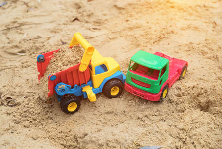children's toys trucks on the sand imitate a traffic accident, an accident in sandbox after a rain in the autumn,の写真素材