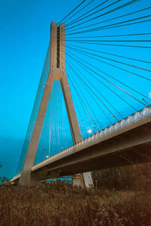 Cable-stayed bridge close-up in the evening against a background of blue sky and cloudsの写真素材