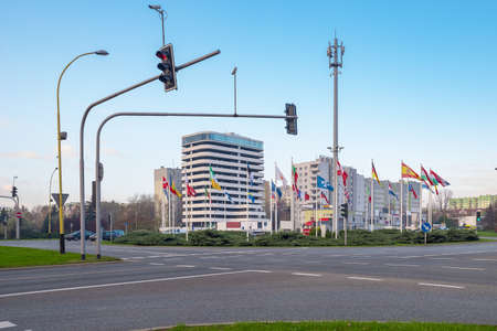Crossroad and flags countries near roadway against backdrop large modern business office building...
