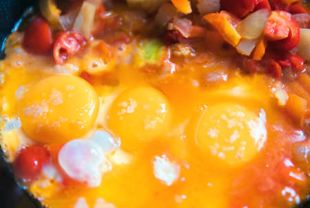 Fried eggs and stewed vegetables in a frying pan closeupの写真素材