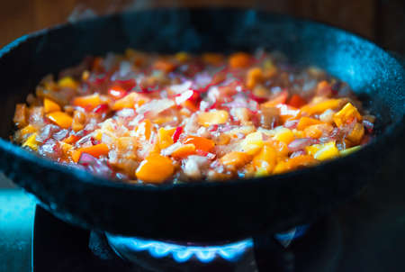 Chopped vegetables pepper onion tomatoes during frying in a frying pan