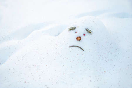 Sad snowdrift, a snowman, in anticipation of spring, is looking as warm rays are selected up to him. Snowdrift in the shape of a sad face snowman is waiting for him to disappear in springの写真素材