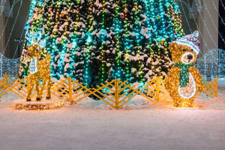 Christmas deer and bear. Garlands outside decorate the street. Holiday lights in the form of a fawn and bear on the street on Christmas Eve. Christmas tree on the street in toys.の写真素材