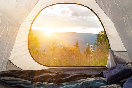 View from the tourist tent on the mountains, meadow, flowers, early in the morning when the sun rises. tourist tentの写真素材