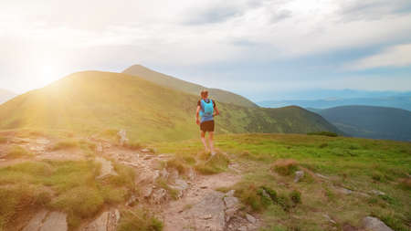 Early morning in the mountains. Young man runs on a trail in the mountains. Background illustrating...