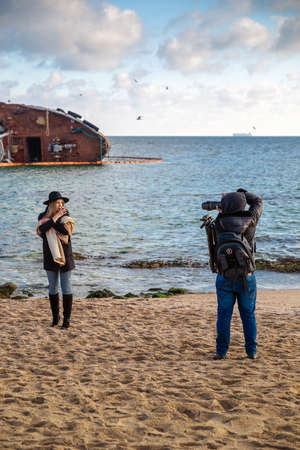 Odessa, Ukraine, December 2019: Photographer teen taking photos of female model on beach at sunset. Photo sessionのeditorial素材