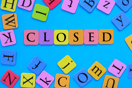 The word closed spelled in multi colored letters and blue background. Concept of closed schools and daycare centersの写真素材