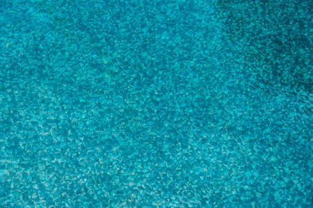 Mosaic bottom of swimming pool when watched through wave ripple.