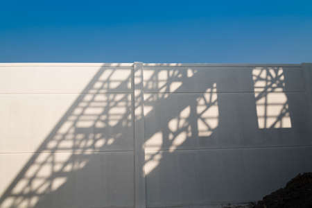 Shadows of house roof beam on the fence.の写真素材