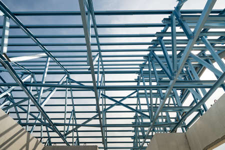 Structure of steel roof frame for building construction on sky background.
