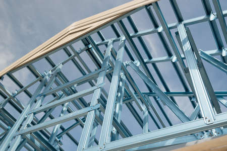 Structure of steel roof frame for building construction on sky background.