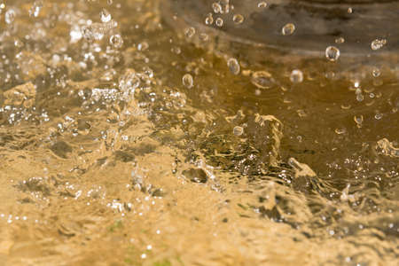 Blurred motion of water splash on yellow background.