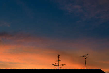 Televisions antenna on top roof with sunset cloudy sky background.の写真素材