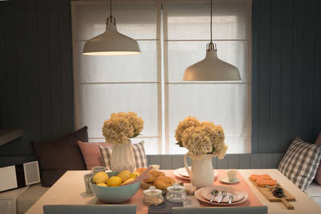 The white lamp hanging from the ceiling floor over dining table.