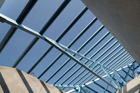 Structure of steel roof frame for building construction isolated on blue sky background.