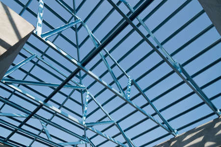 Structure of steel roof frame for building construction isolated on blue sky background.