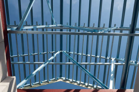 Structure of steel roof frame for building construction isolated on blue sky background.