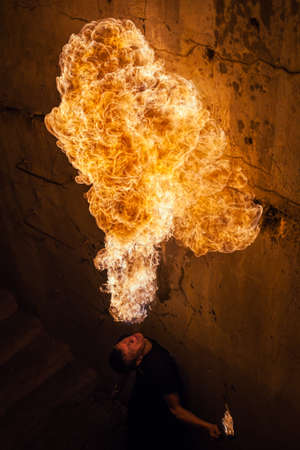 Fire artist blowing fire from his mouthの写真素材