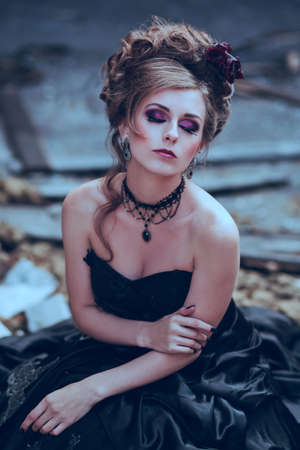 Mysterious woman dressed in gothic dress posing in ruined building