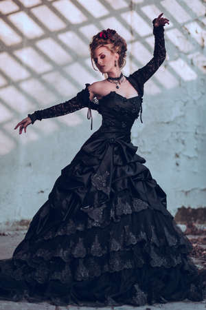 Mysterious woman dressed in gothic dress posing in ruined buildingの写真素材