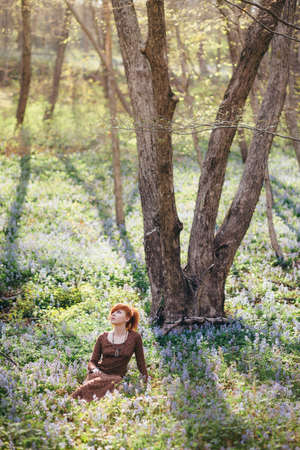 Beautiful young woman in the forest with spring flowersの写真素材