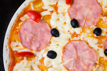 Appetizing pizza with mozzarella cheese, ham and tomatoesの写真素材