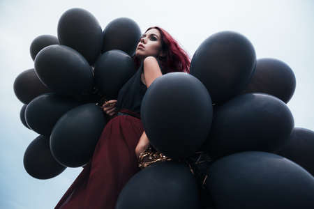 Beautiful girl walking with black balloonsの写真素材