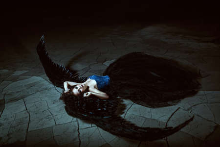 Pretty girl-demon with black wings behind her backの写真素材