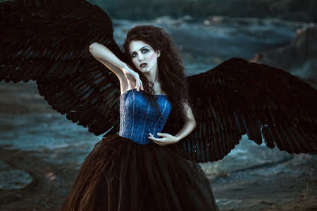 Pretty girl-demon with black wings behind her backの写真素材