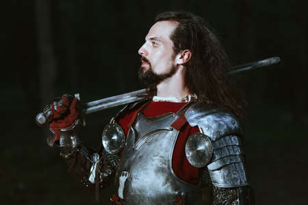 Knight dressed in armor walking in dark forestの写真素材