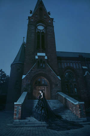 Woman in black gothic dress near chirch