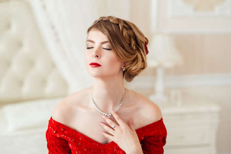 Beautiful woman in a red dress lying on bed.