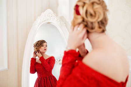 Woman dressed in red dress looking in mirror