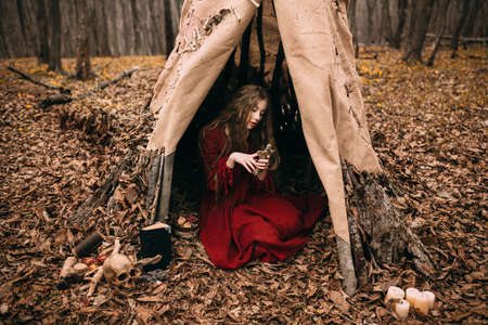 Young woman in red dress in the autumn forest