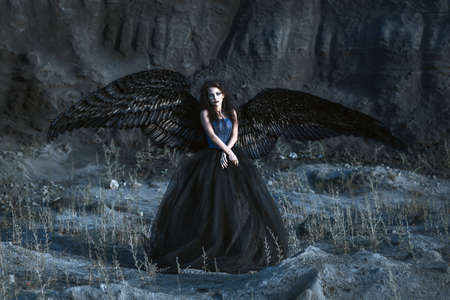 Pretty girl-demon with black wings behind her backの写真素材