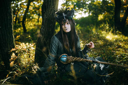Woman-shaman with horns in green dress walk in forest
