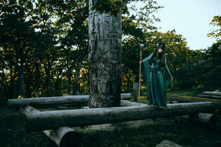 Woman-shaman with horns in green dress walk in forestの写真素材