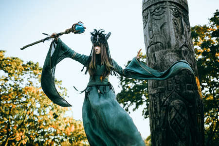 Woman-shaman with horns in green dress walk in forestの写真素材