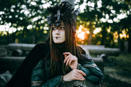 Woman-shaman with horns in green dress walk in forestの写真素材