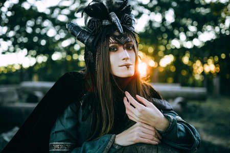 Woman-shaman with horns in green dress walk in forest