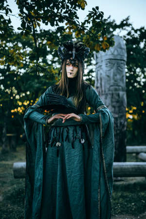 Woman-shaman with horns in green dress walk in forestの写真素材