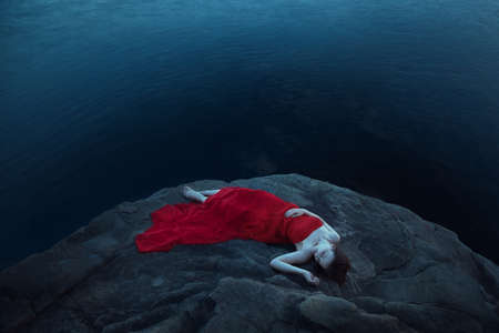 A sad woman near the sea in eveningの写真素材