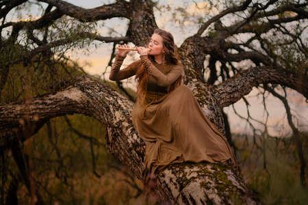 Redhead woman in dress walking in fantasy fairy tale forestの写真素材