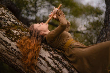 Redhead woman in dress walking in fantasy fairy tale forestの写真素材